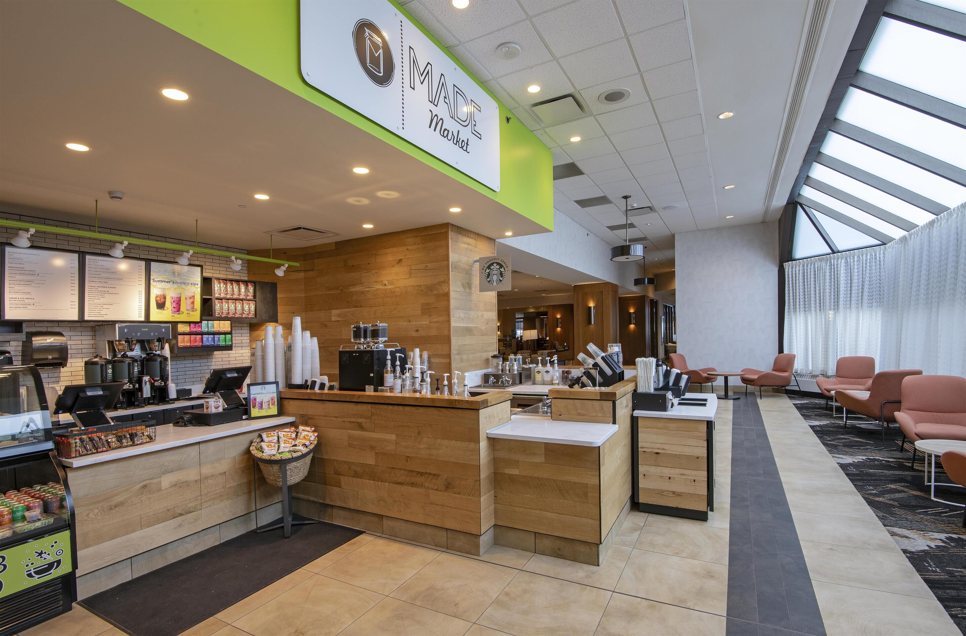 A modern indoor market with a wooden counter, a Starbucks logo, and seating areas.