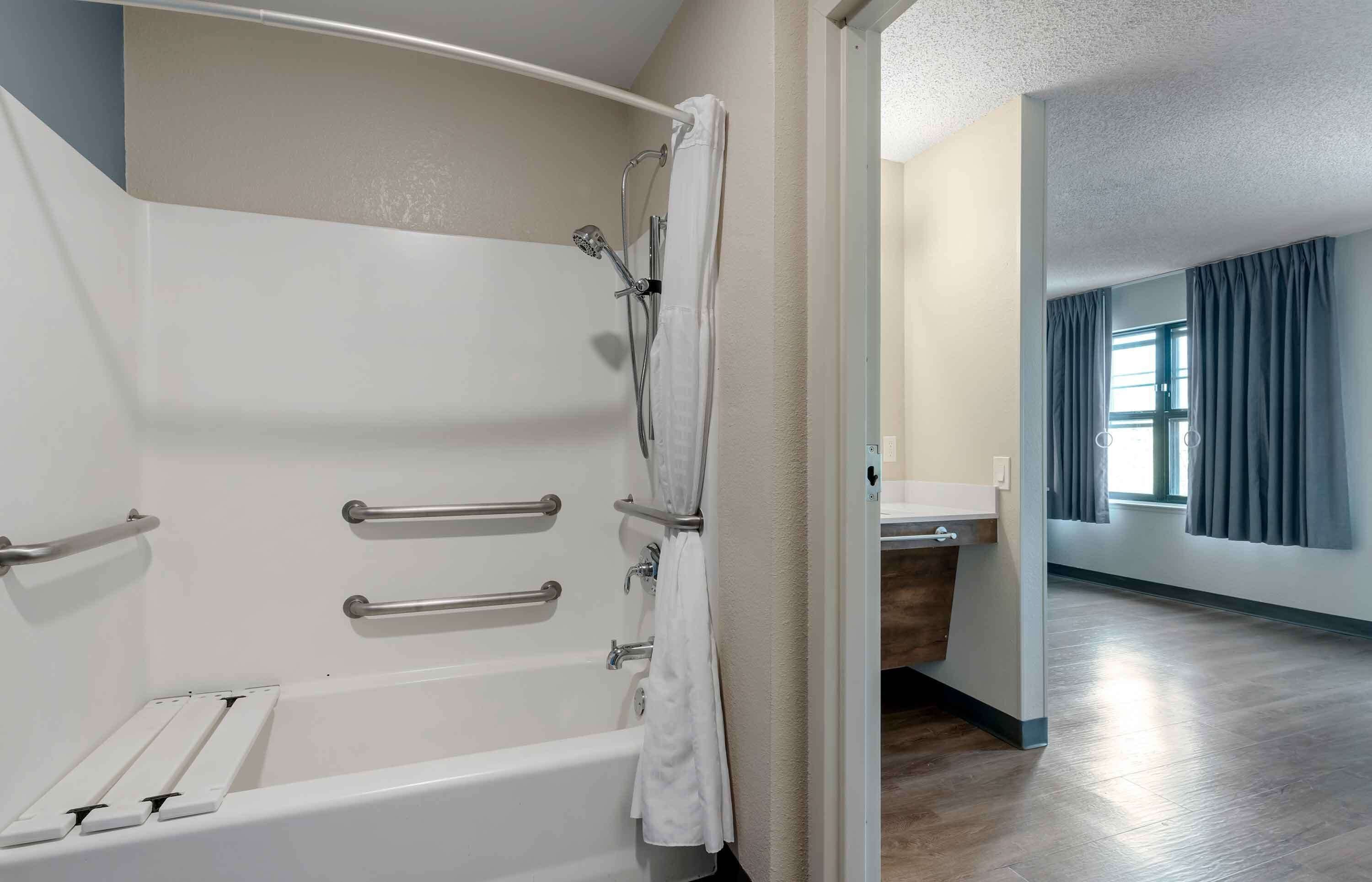 Un baño moderno con bañera, barras de apoyo y ducha.