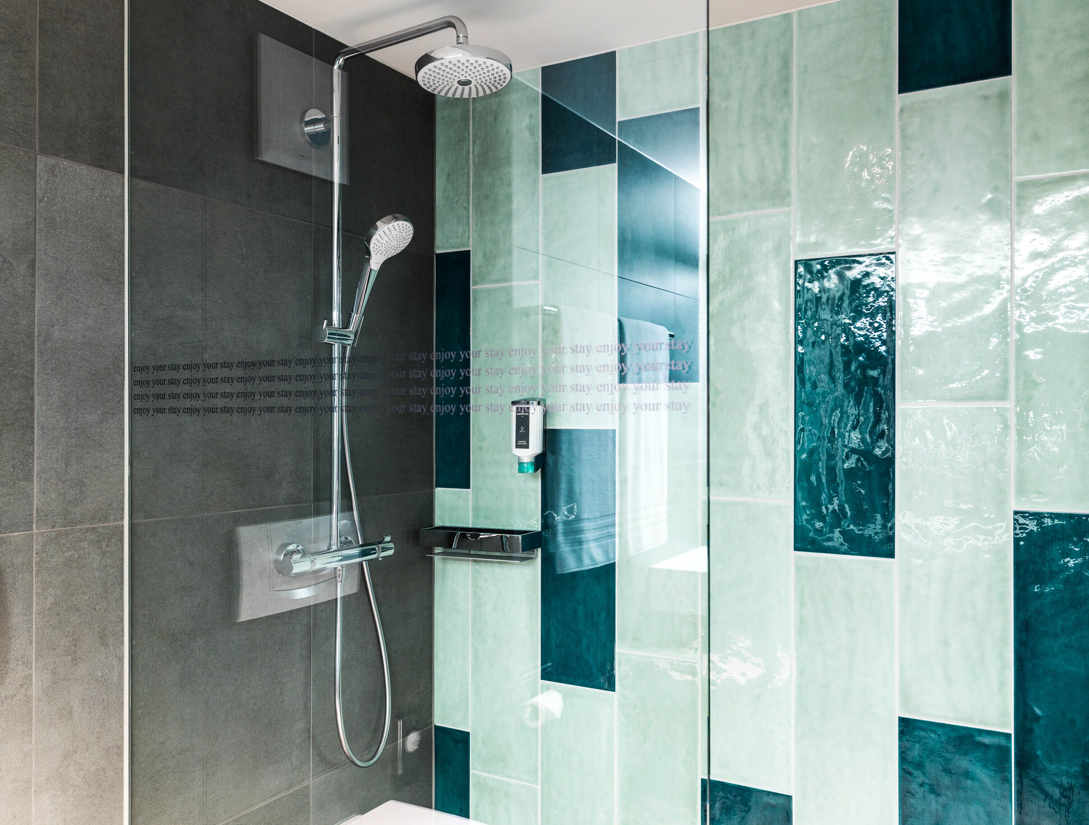 A modern bathroom with a glass-enclosed shower, a handheld showerhead, and a wall-mounted control panel.