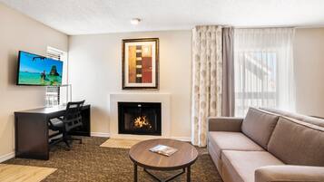 Una sala de estar con chimenea, un sofá, una mesa de centro, un televisor y un escritorio.