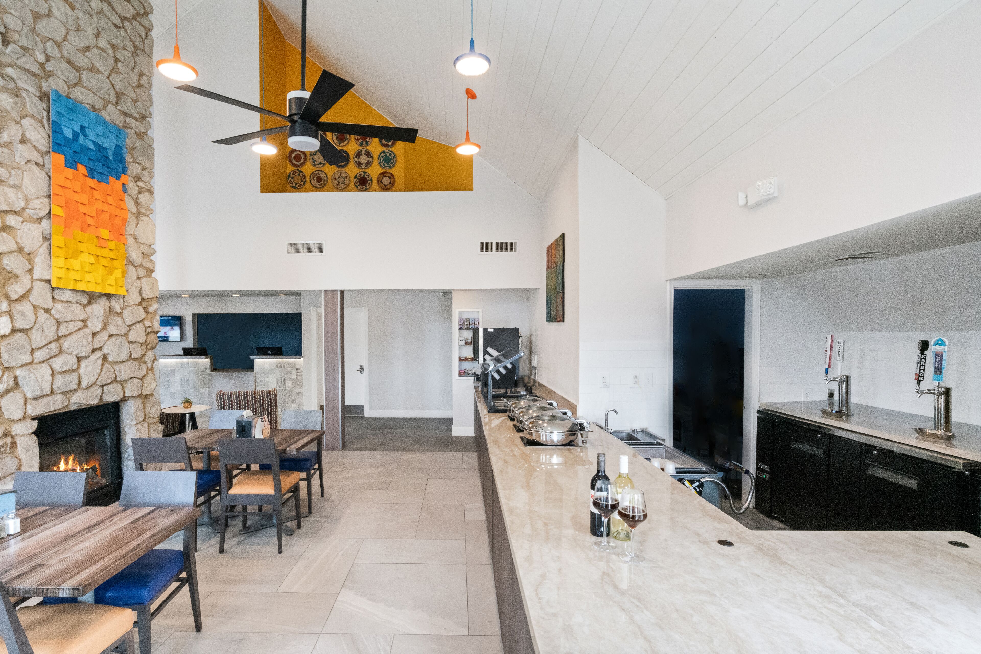 Une cuisine moderne avec un mur d’accent en pierre, un bar intégré et un ventilateur de plafond.