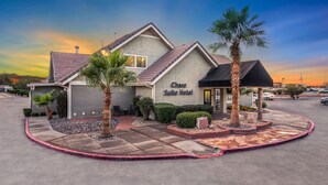 A Chase Suite Hotel with a modern design, featuring a landscaped front yard with palm trees and a patio area. - Chase Suite Hotel El Paso (El Paso)