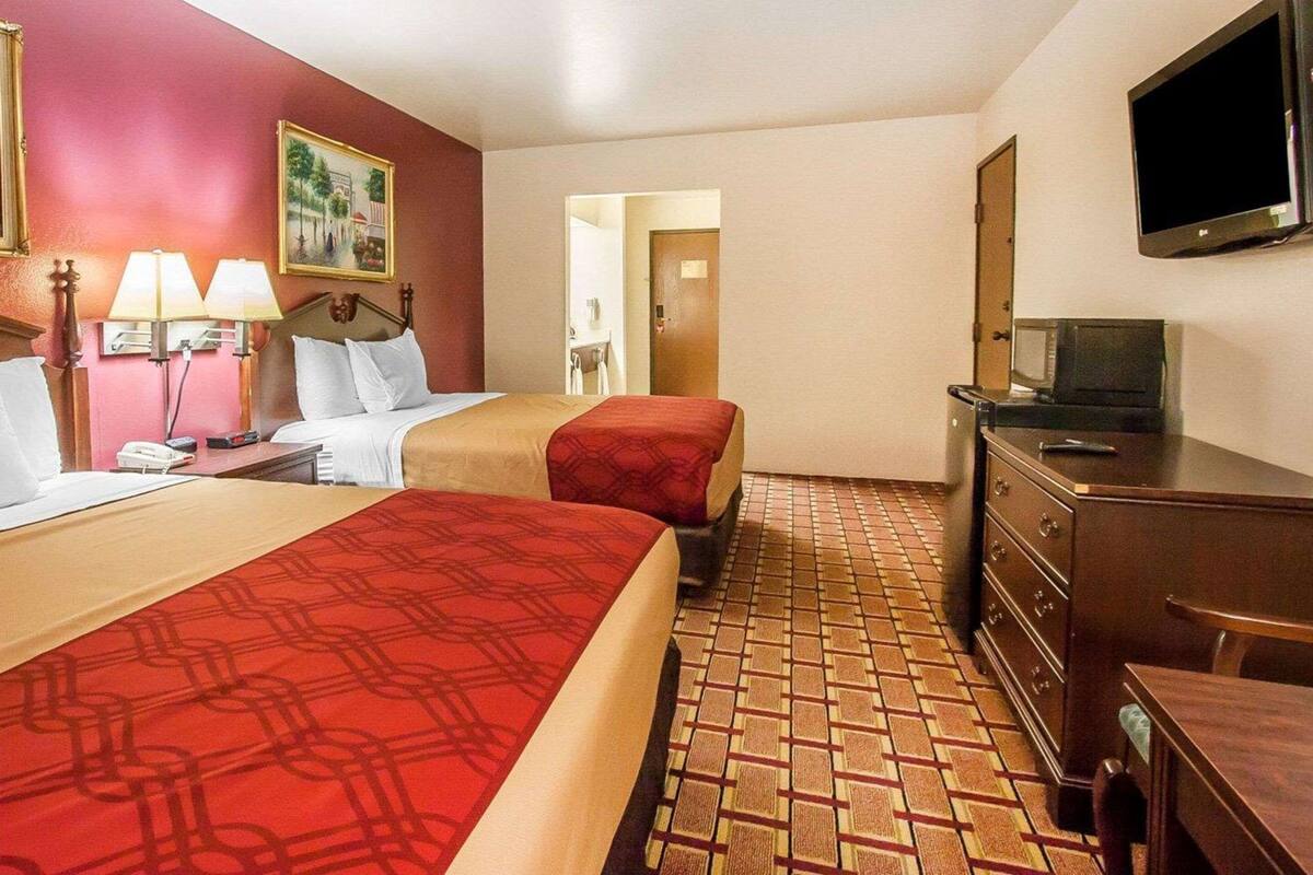 A hotel room with two beds, a television, a desk, and a dresser.