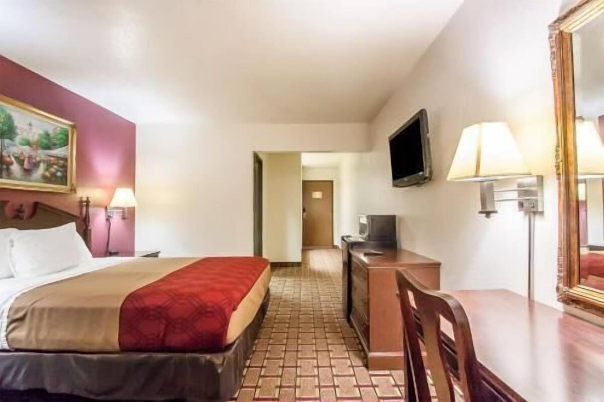 A hotel room with a bed, a desk, a television, and a mirror.