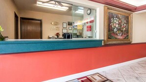 A hotel reception area with a reception desk, framed certificates, and a painting on the wall. - Econo Lodge Dexter (Dexter)