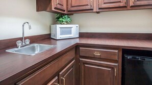 A kitchen with wooden cabinets, a stainless steel sink, a microwave, and a dishwasher. - Econo Lodge Dexter (Dexter)