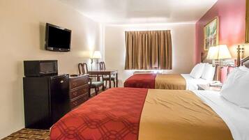 A hotel room with two beds, a desk with a chair, a television, and a window with curtains.