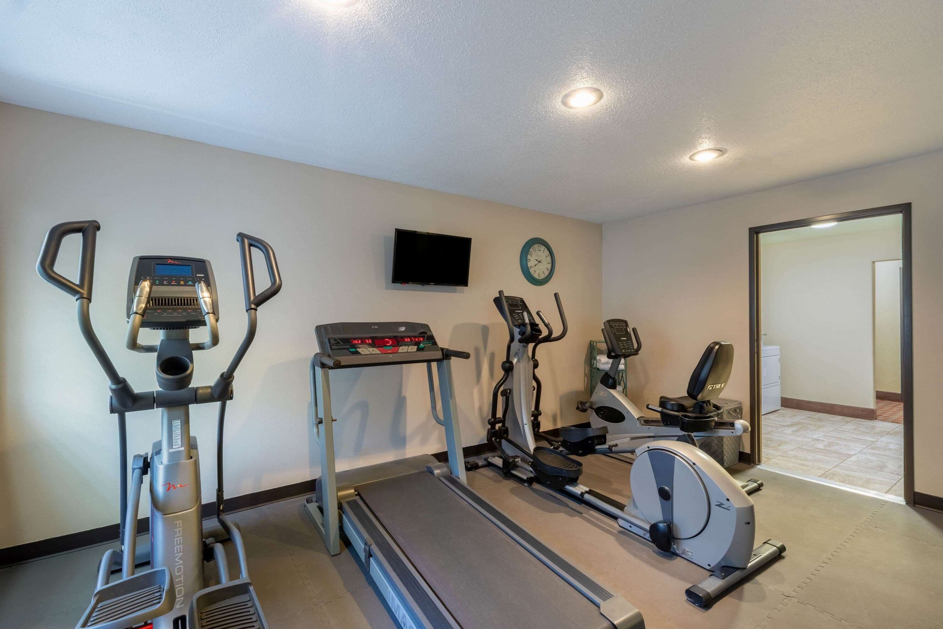 Un gimnasio en casa con cinta de correr, elíptica y bicicleta estática.