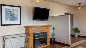 Una sala de estar con chimenea, un televisor en la pared y un mapa enmarcado.