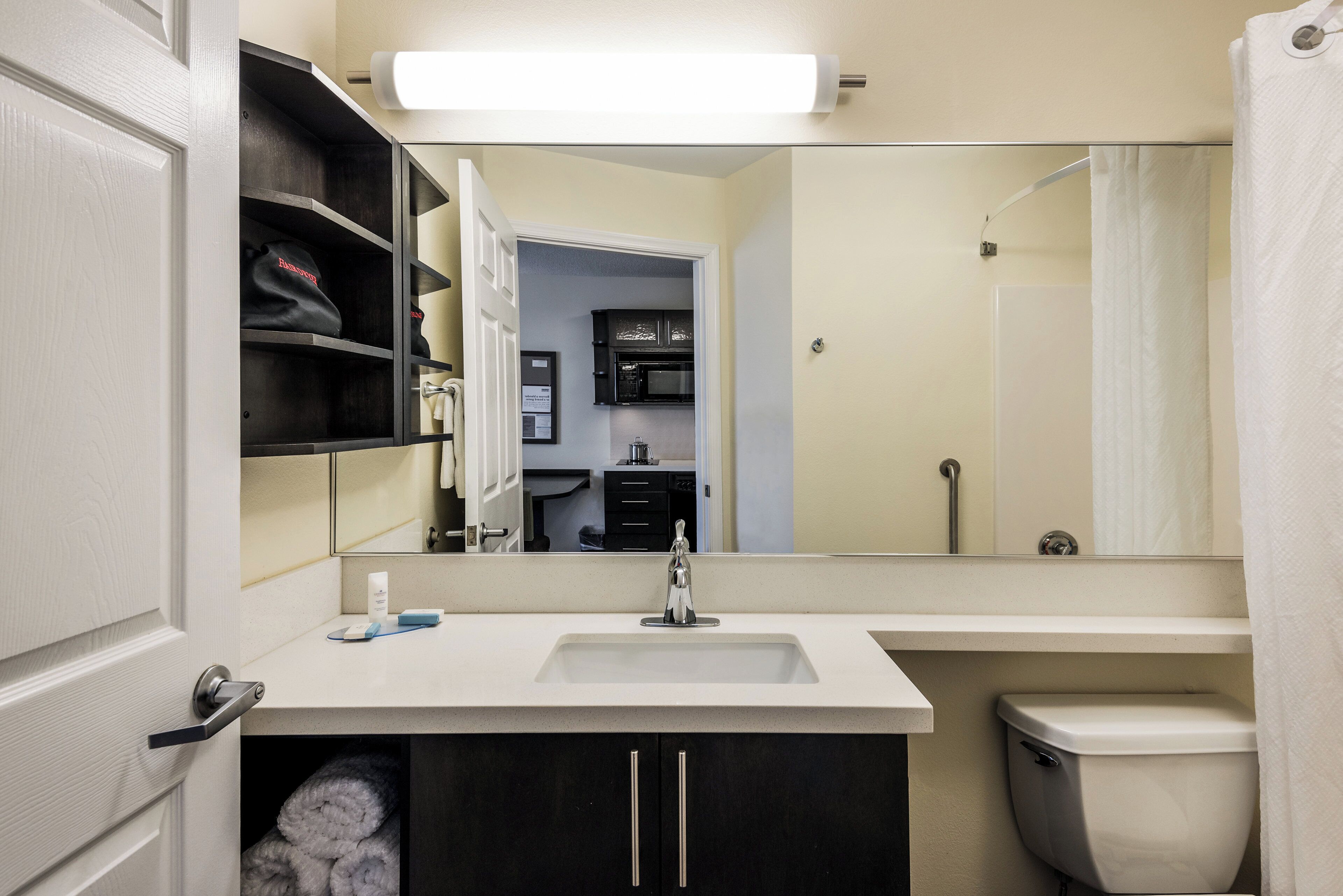 A bathroom with a white sink, a mirror, a toilet, and a shower curtain.