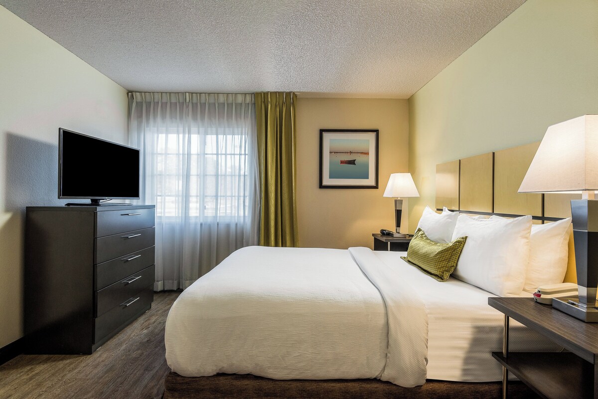 A hotel room with a bed, a TV, a desk, and a lamp.