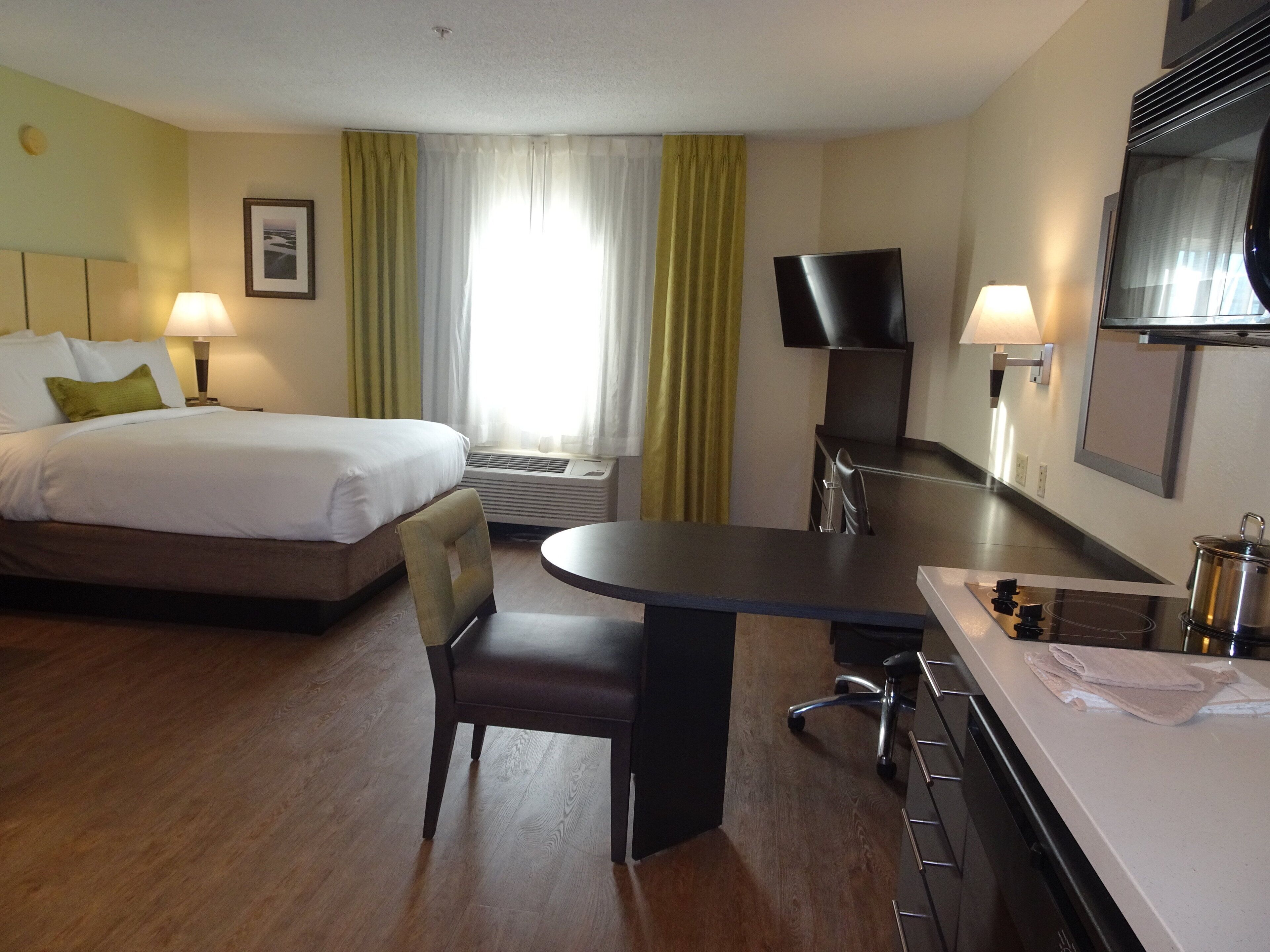 A hotel room with a bed, a desk, a chair, a television, and a bathroom.