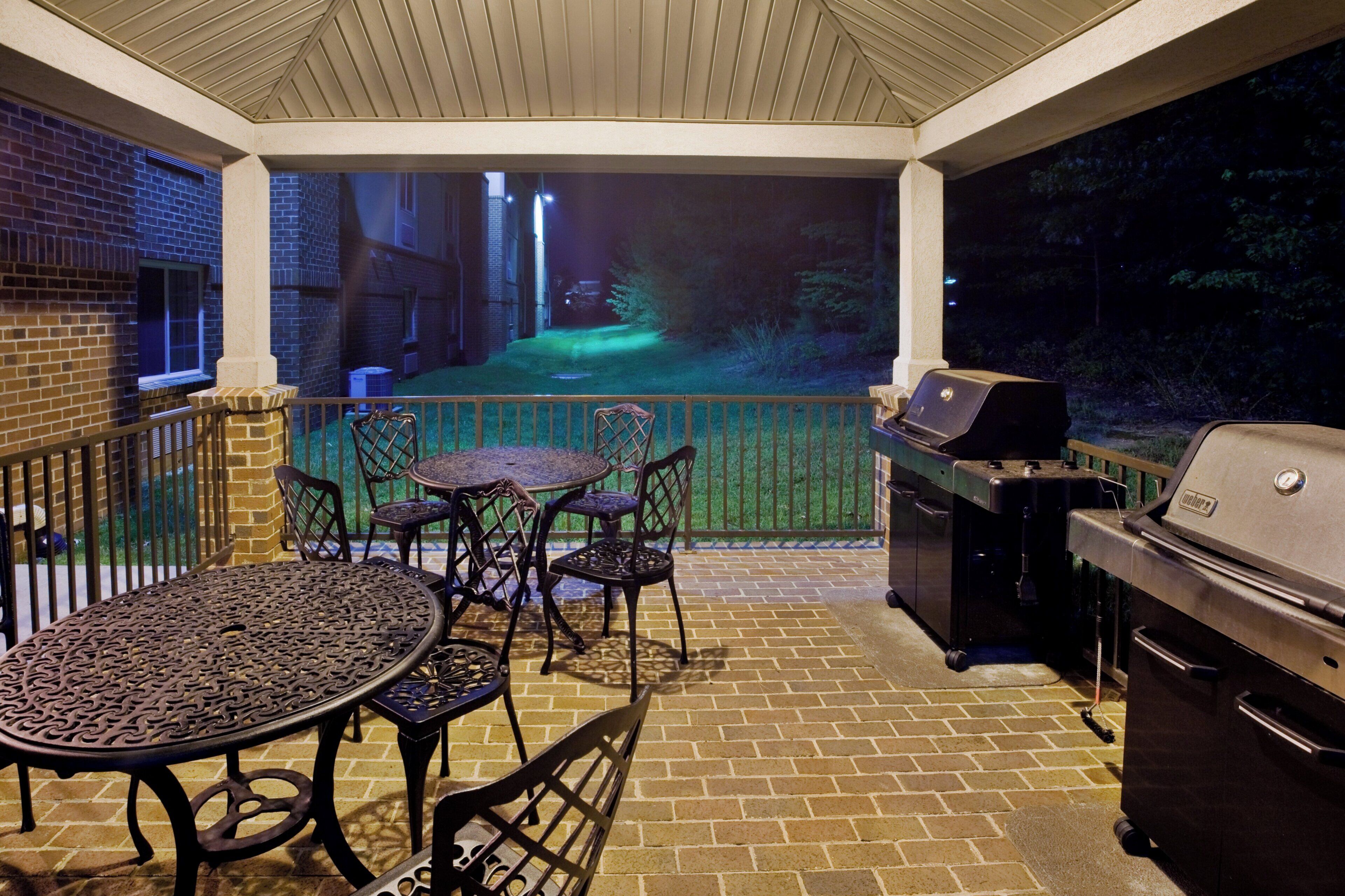 A covered patio with a grill and outdoor furniture.