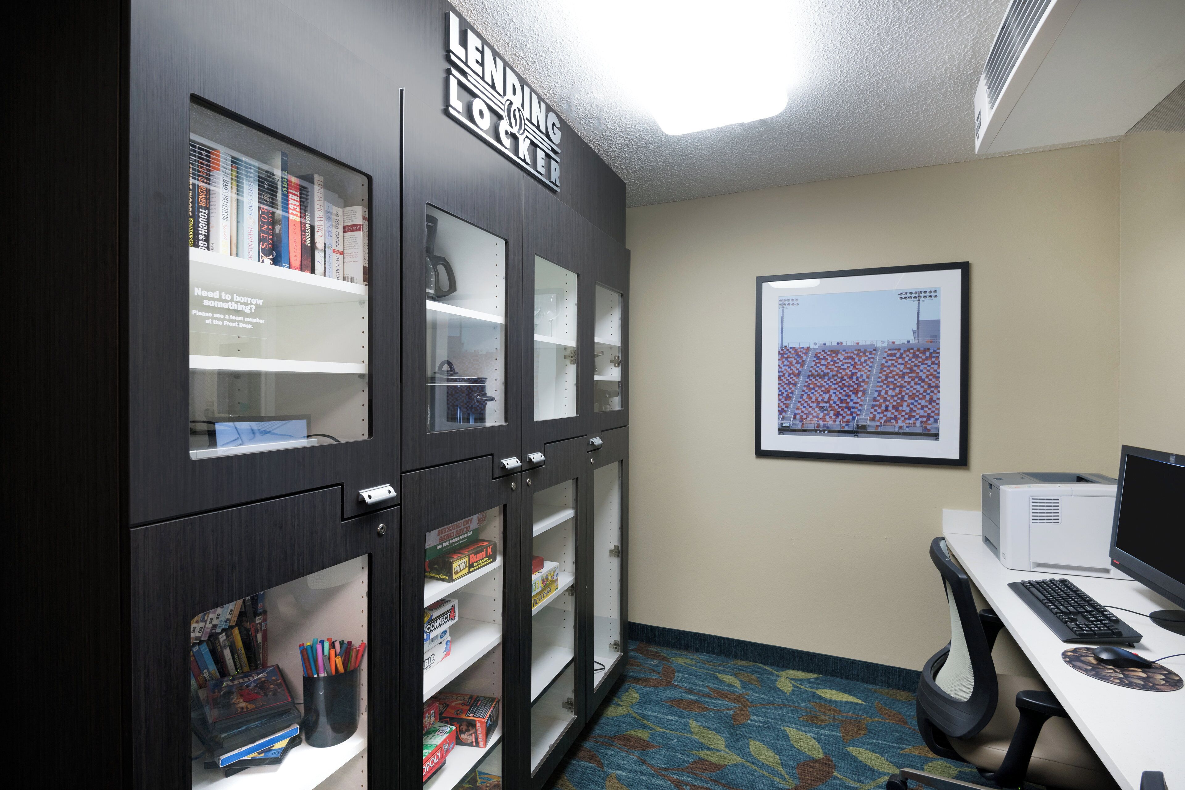 A room with a desk, computer, and a bookshelf with various items.