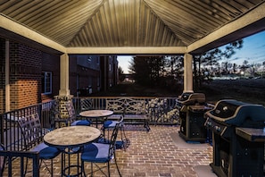 Une terrasse extérieure avec un sol en briques, une clôture en métal et un barbecue.