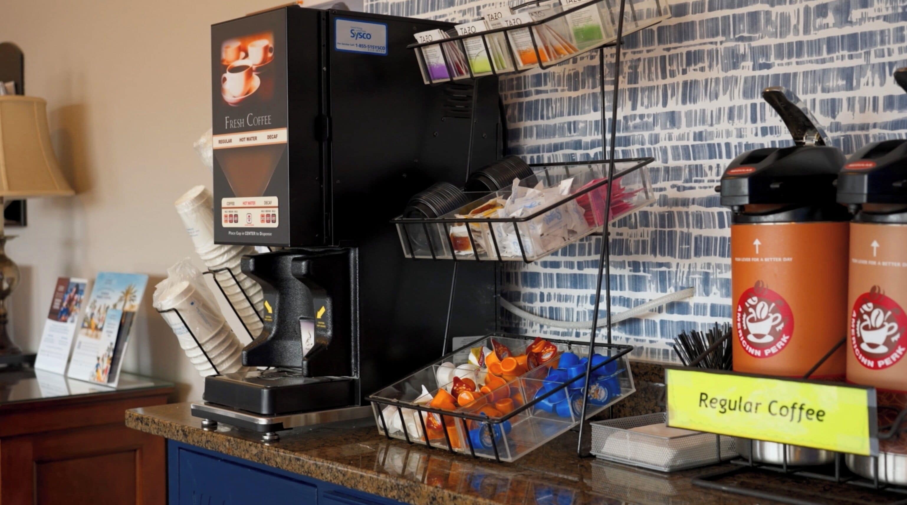A coffee station with a coffee machine, multiple coffee pods, and a sign for regular coffee.