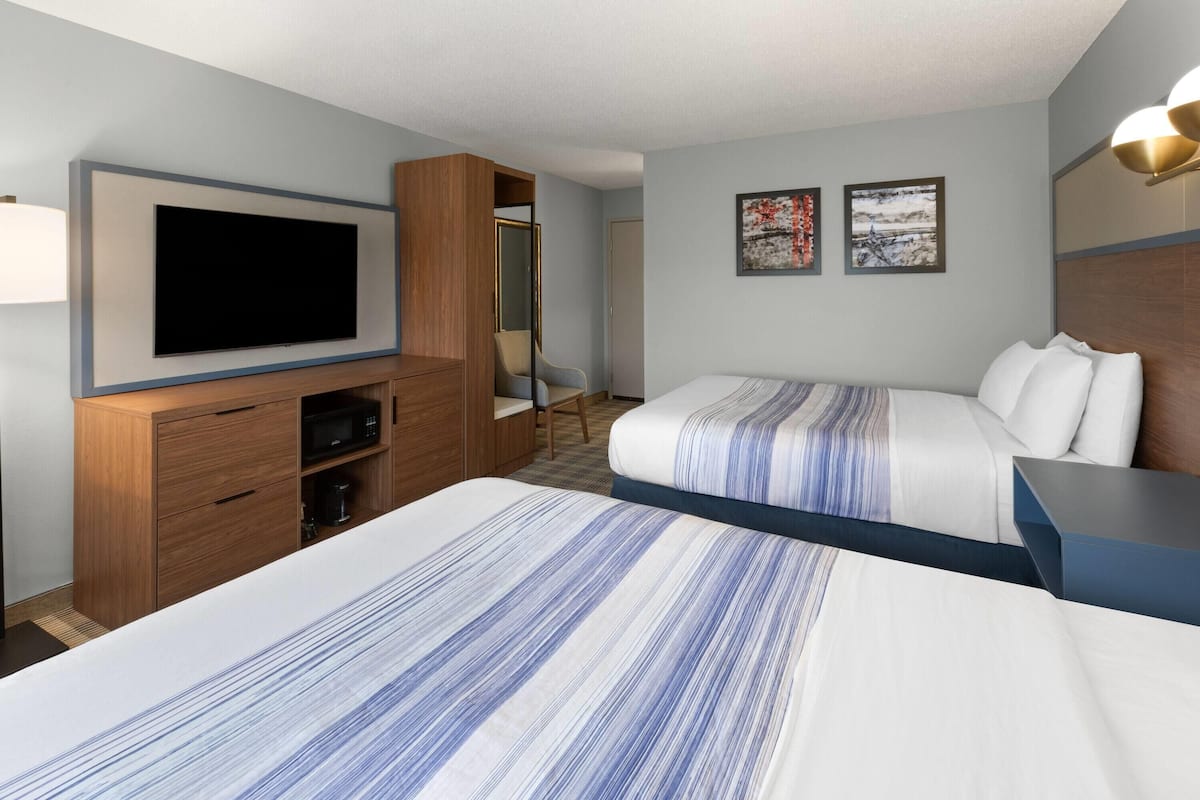 A hotel room with a large bed, a TV mounted on the wall, a wardrobe, and two framed pictures on the wall.