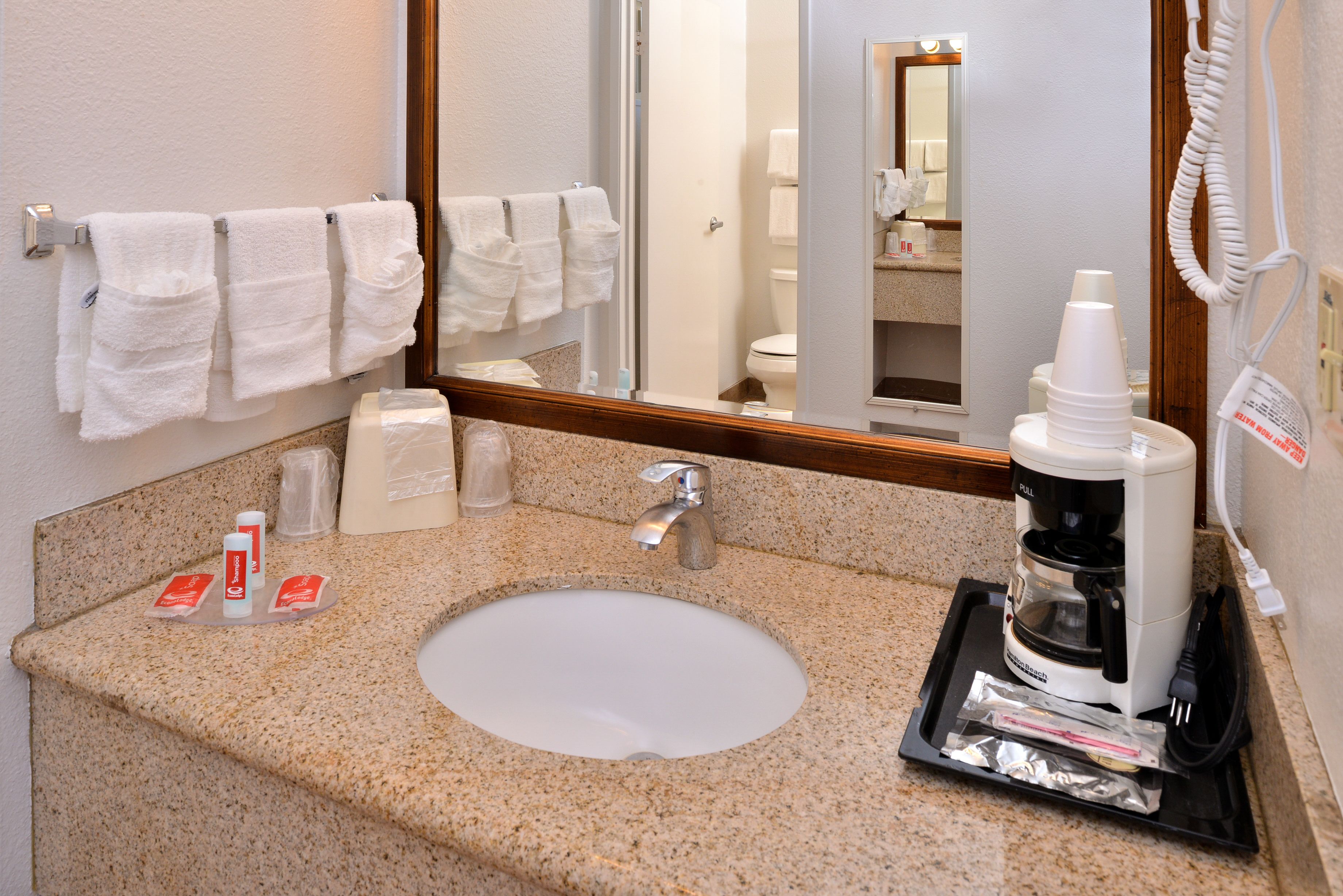 A bathroom with a sink, a coffee maker, and a mirror.