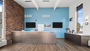 A reception area with a stone wall, blue walls, wooden flooring, and a counter with a sign indicating accessibility.