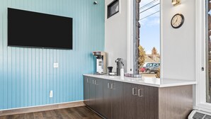 A kitchen with a blue wall, a white countertop, and a clock. - Bend Inn & Suites (Bend)