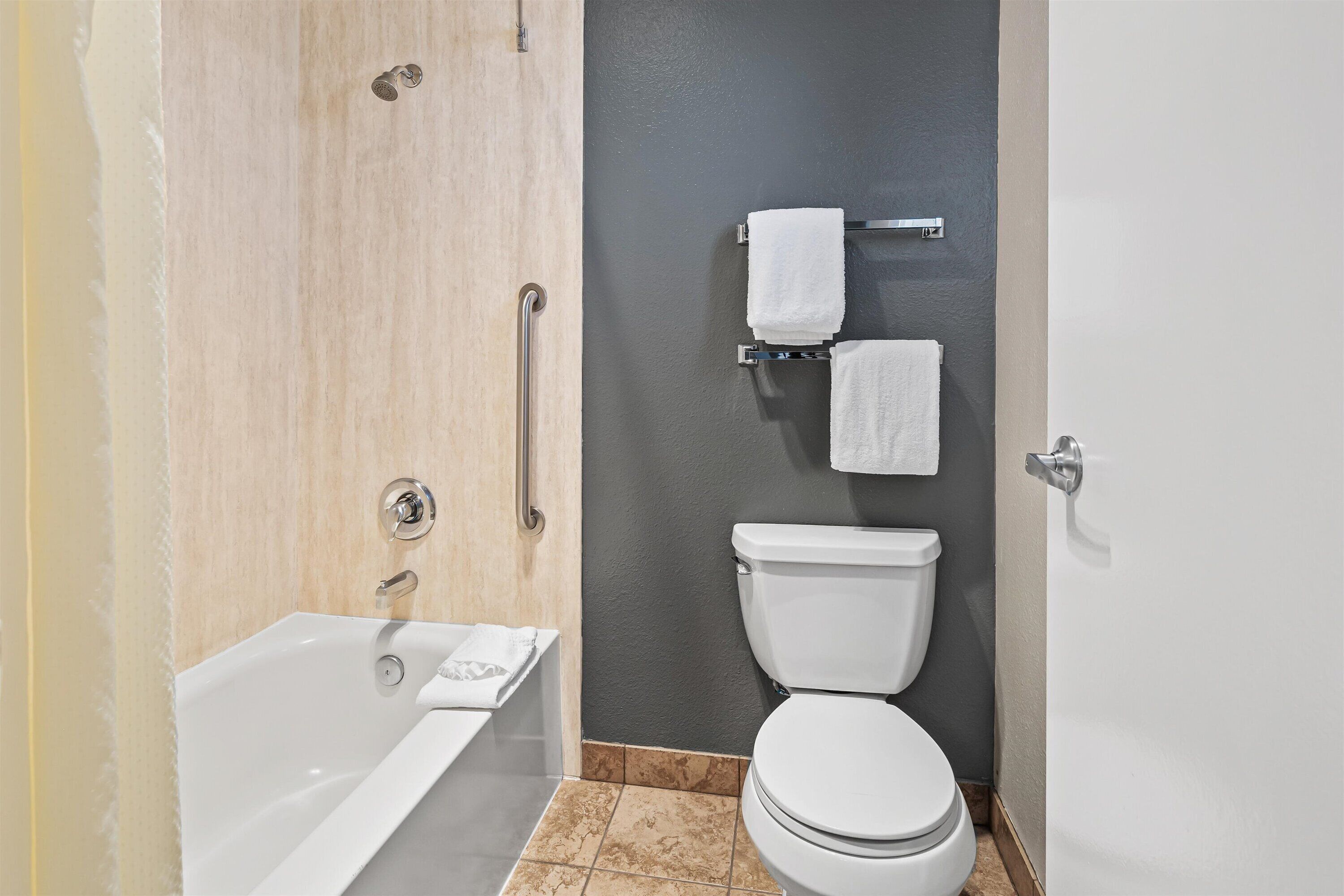 Une salle de bain moderne équipée d’une baignoire, de toilettes et d’un porte-serviettes.