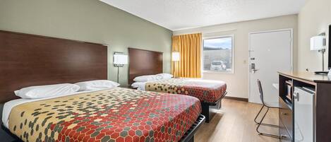 A hotel room with two beds, a desk, and a window with a view.