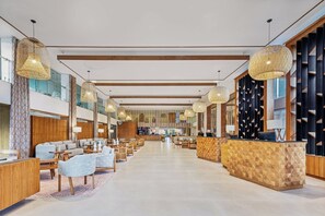 Eine geräumige Lobby mit Empfangstresen, Sitzgelegenheiten und hohen Decken mit hängenden Lampen.