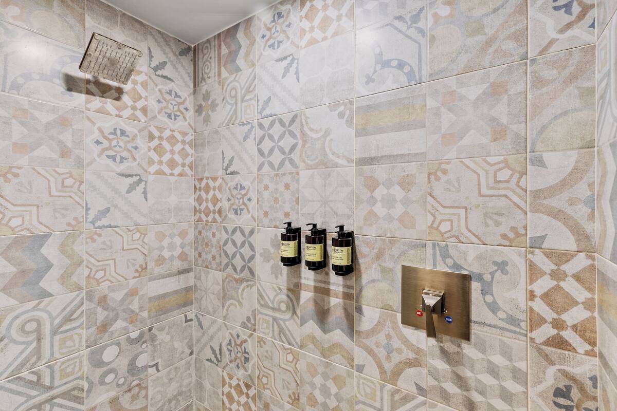 Douchegedeelte met patroontegels en drie flesjes shampoo.