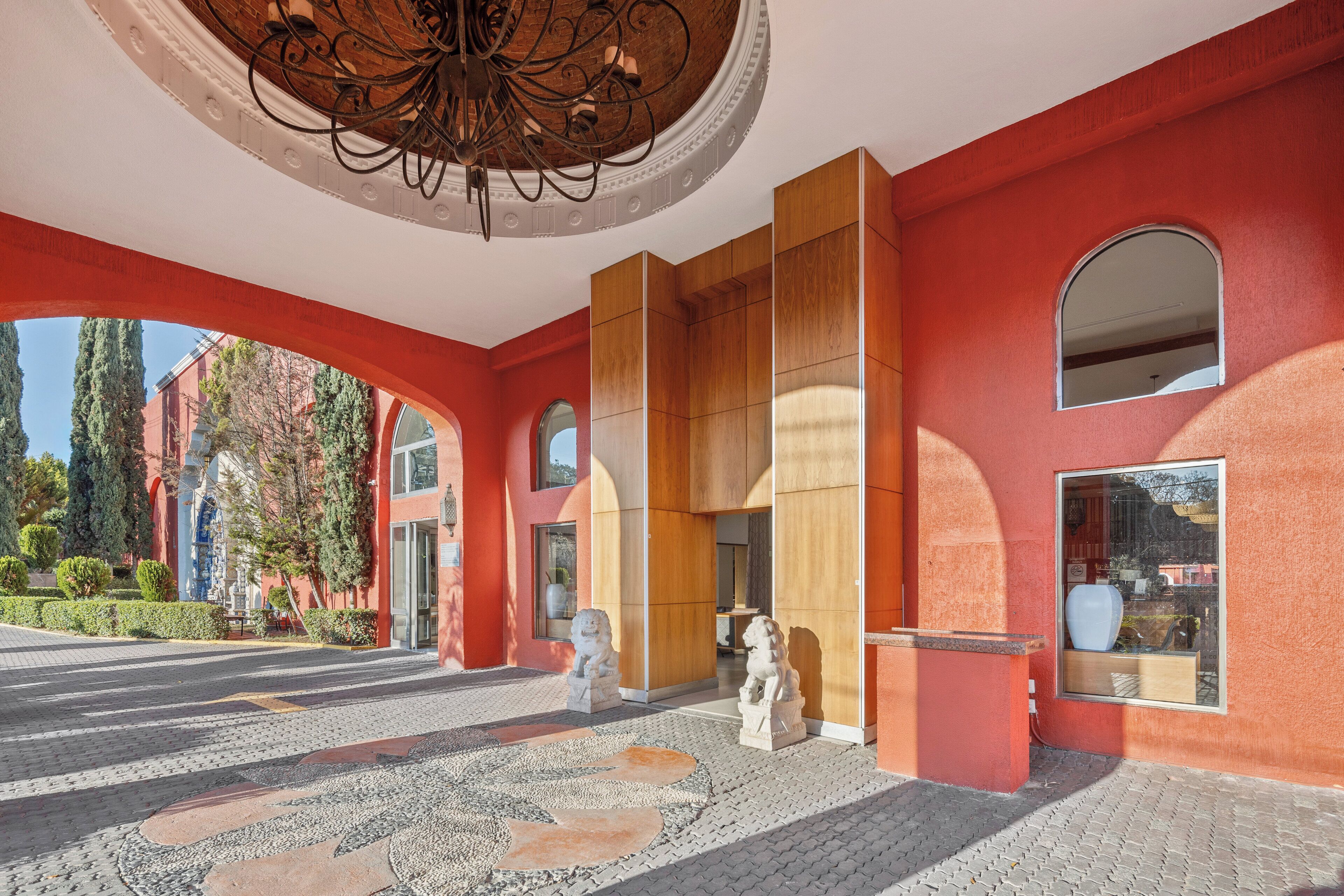 A modern building with red walls, large wooden panels, and a circular mosaic floor.