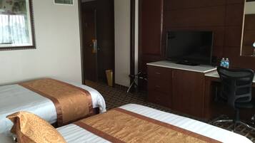 Habitación de hotel con dos camas, un escritorio con televisor y una silla.