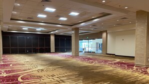 A spacious indoor area with a patterned carpet, ceiling lights, and a glass door entrance. - LA Crystal Hotel - Los Angeles Area (Compton)