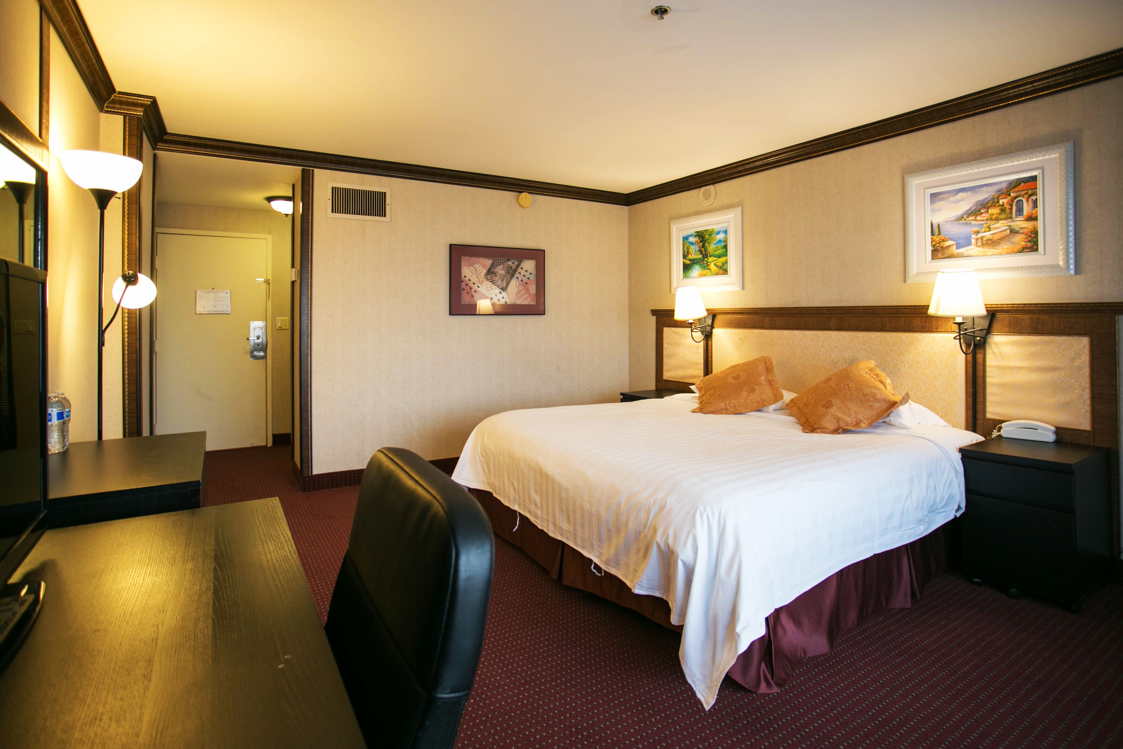 Una habitación de hotel con cama, mesitas de noche, escritorio y una silla.