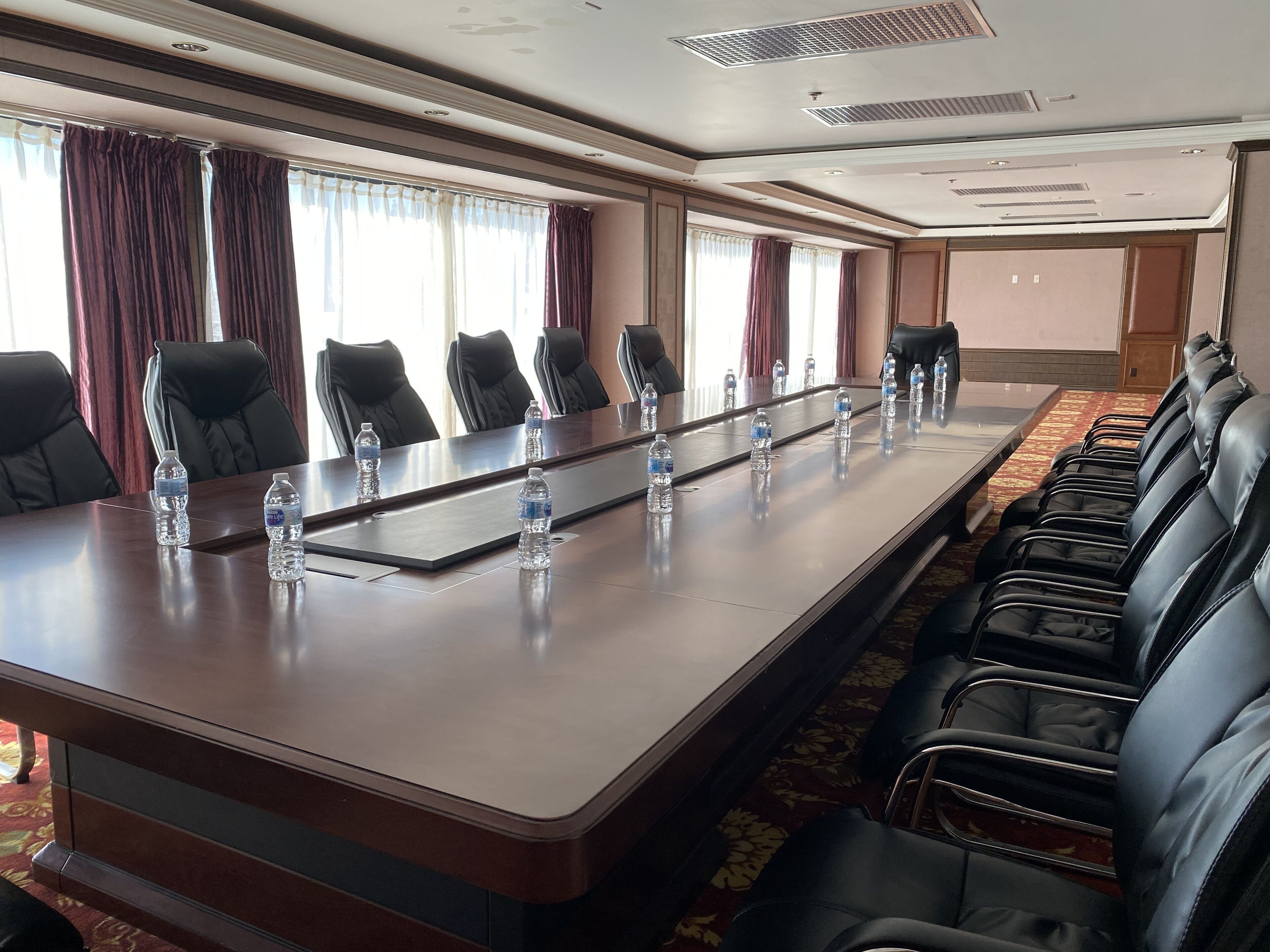 Un salón de conferencias con una larga mesa, varias sillas y botellas de agua.