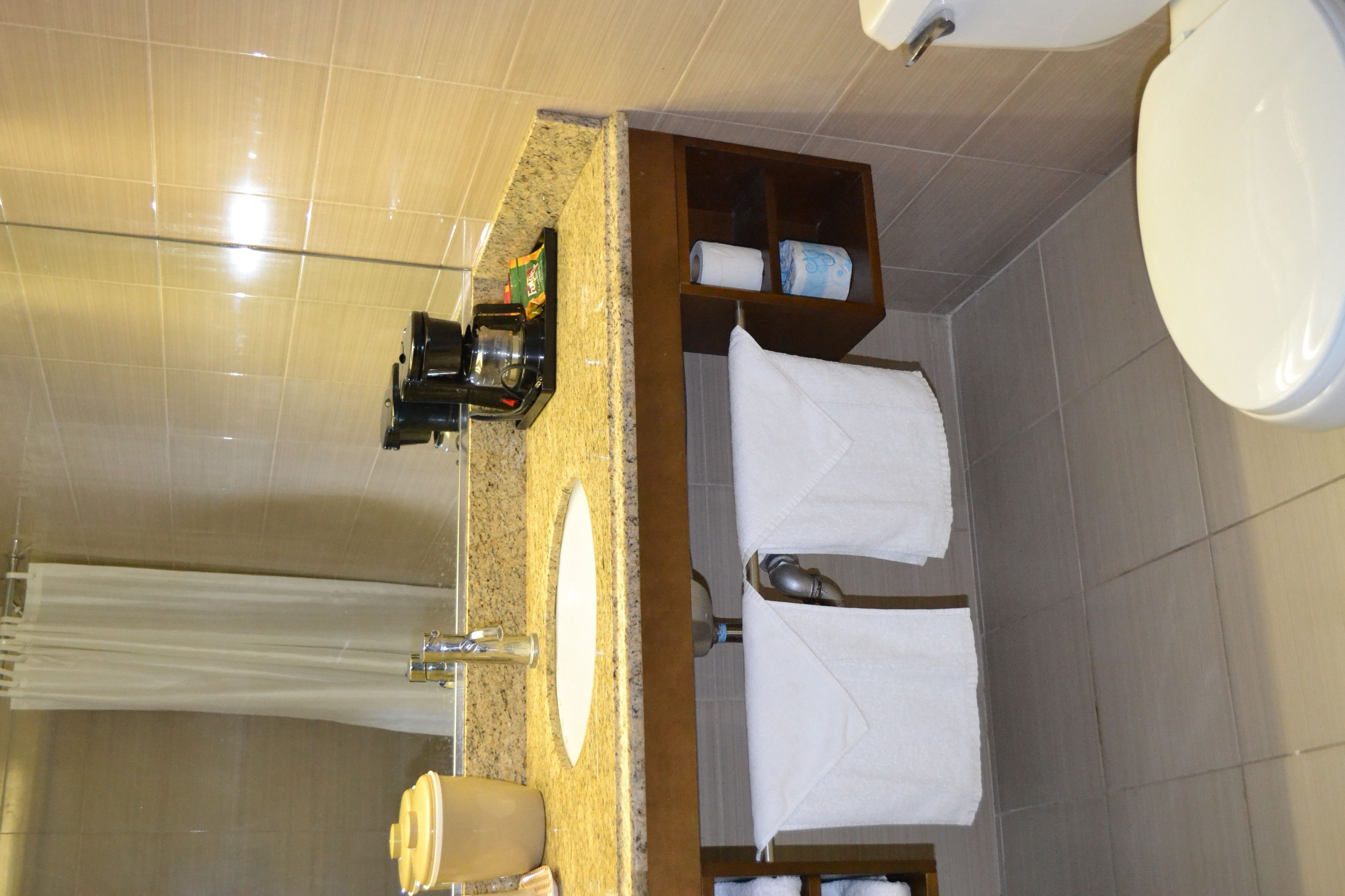 Un baño con encimera de granito, un lavamanos, un espejo y un perchero para toallas.