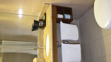 Un baño con encimera de granito, un lavamanos, un espejo y un perchero para toallas.