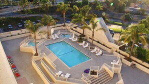 A rooftop pool with multiple lounge chairs and palm trees. - LA Crystal Hotel - Los Angeles Area (Compton)