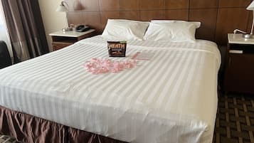 A hotel room with a large bed, a bedside table with a lamp, and a nightstand with a phone.