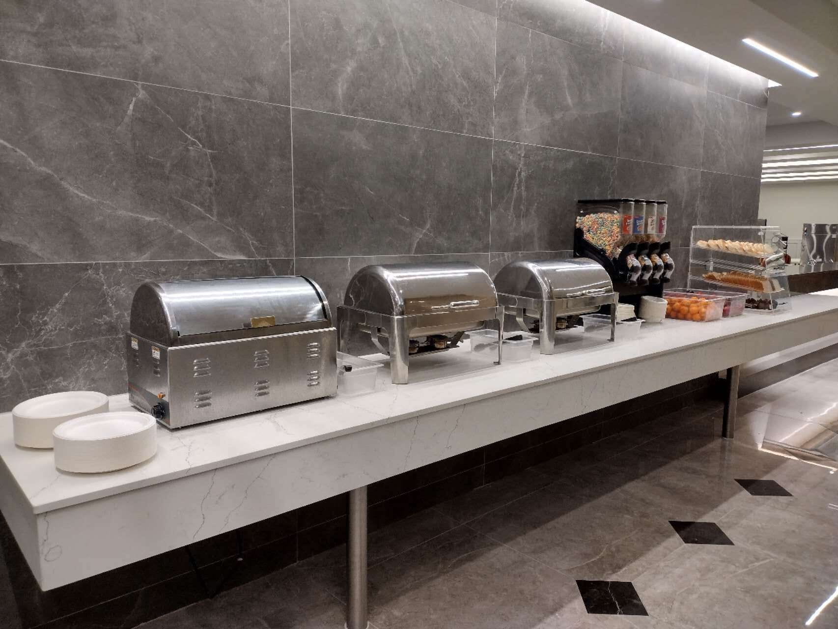 A buffet setup with self-service food dispensers, a beverage dispenser, and a coffee station.