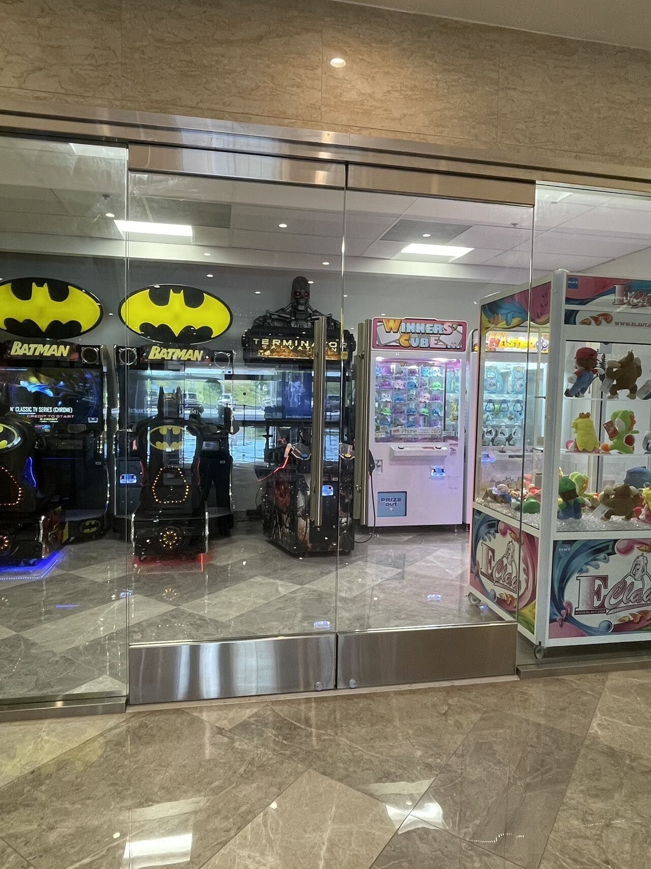 An arcade area with Batman-themed machines, a claw game, and plush toys.