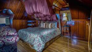 Un dormitorio con cama a dosel, suelo de madera y mesita de noche con lámpara.
