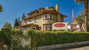 Un edificio grande de dos pisos con un letrero llamativo que dice "Rose Garden Inn".