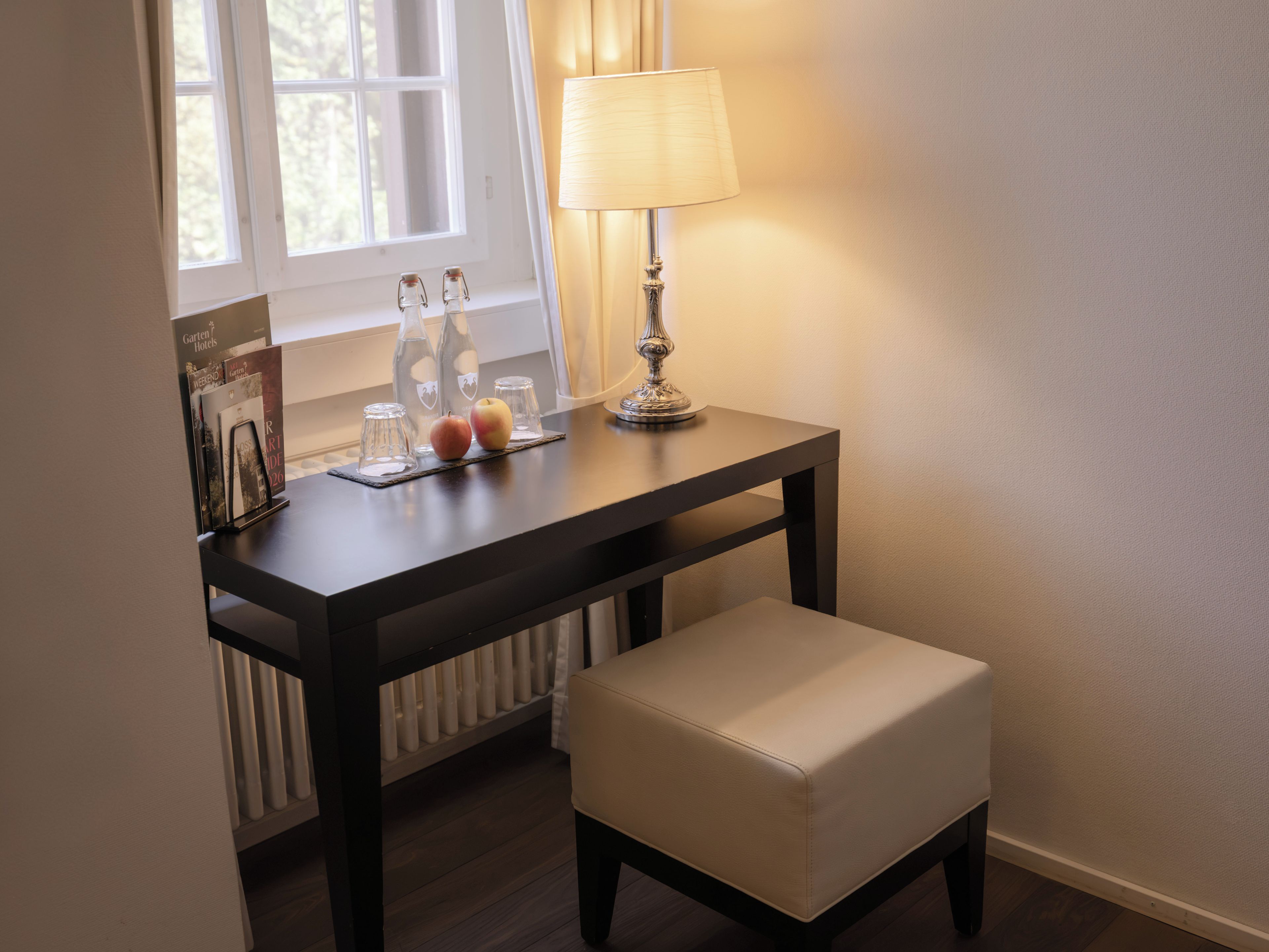 A small table with a lamp, two bottles, and a magazine.