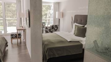 Un dormitorio moderno con cama, mesita de noche, silla y vistas al exterior a través de amplios ventanales.