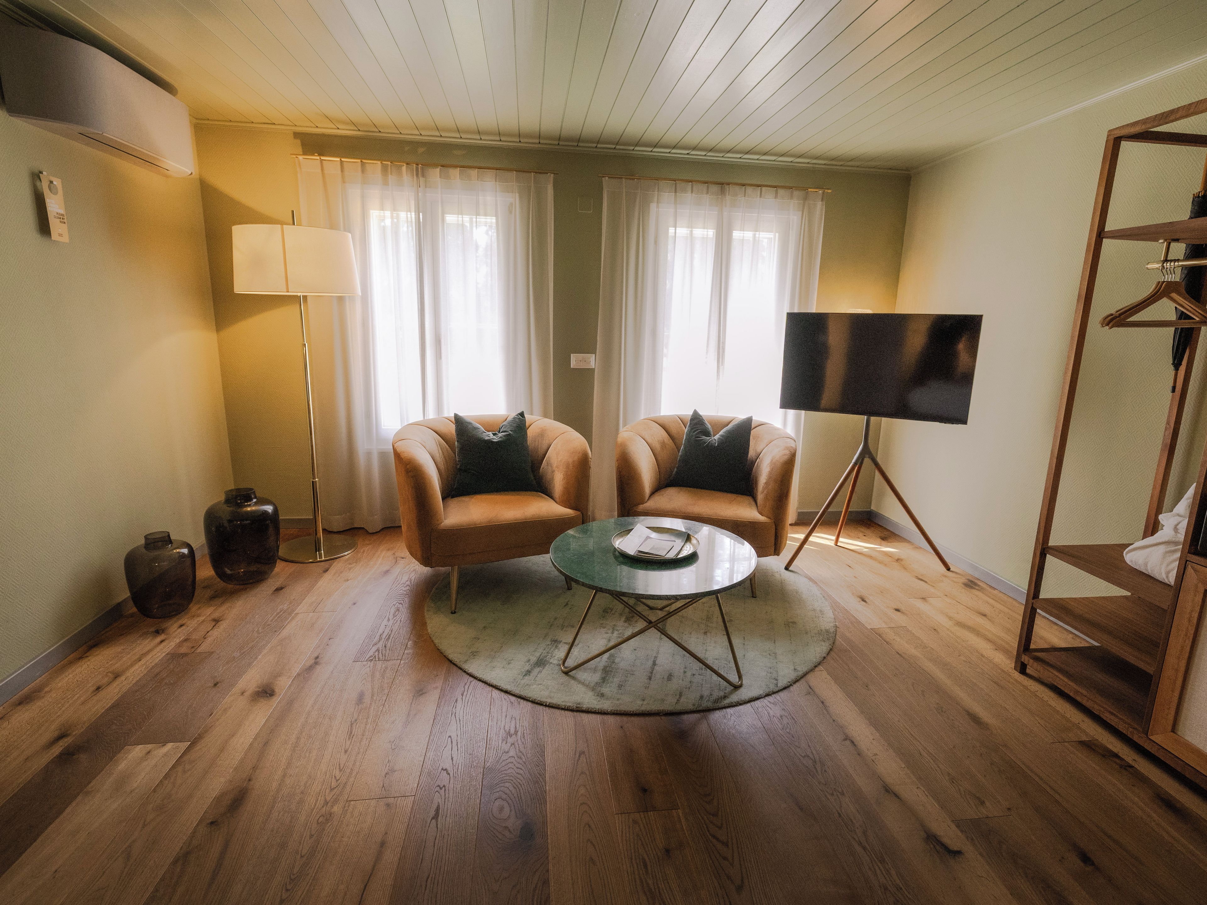 A room with two armchairs, a coffee table, a flat-screen TV, and a floor lamp.