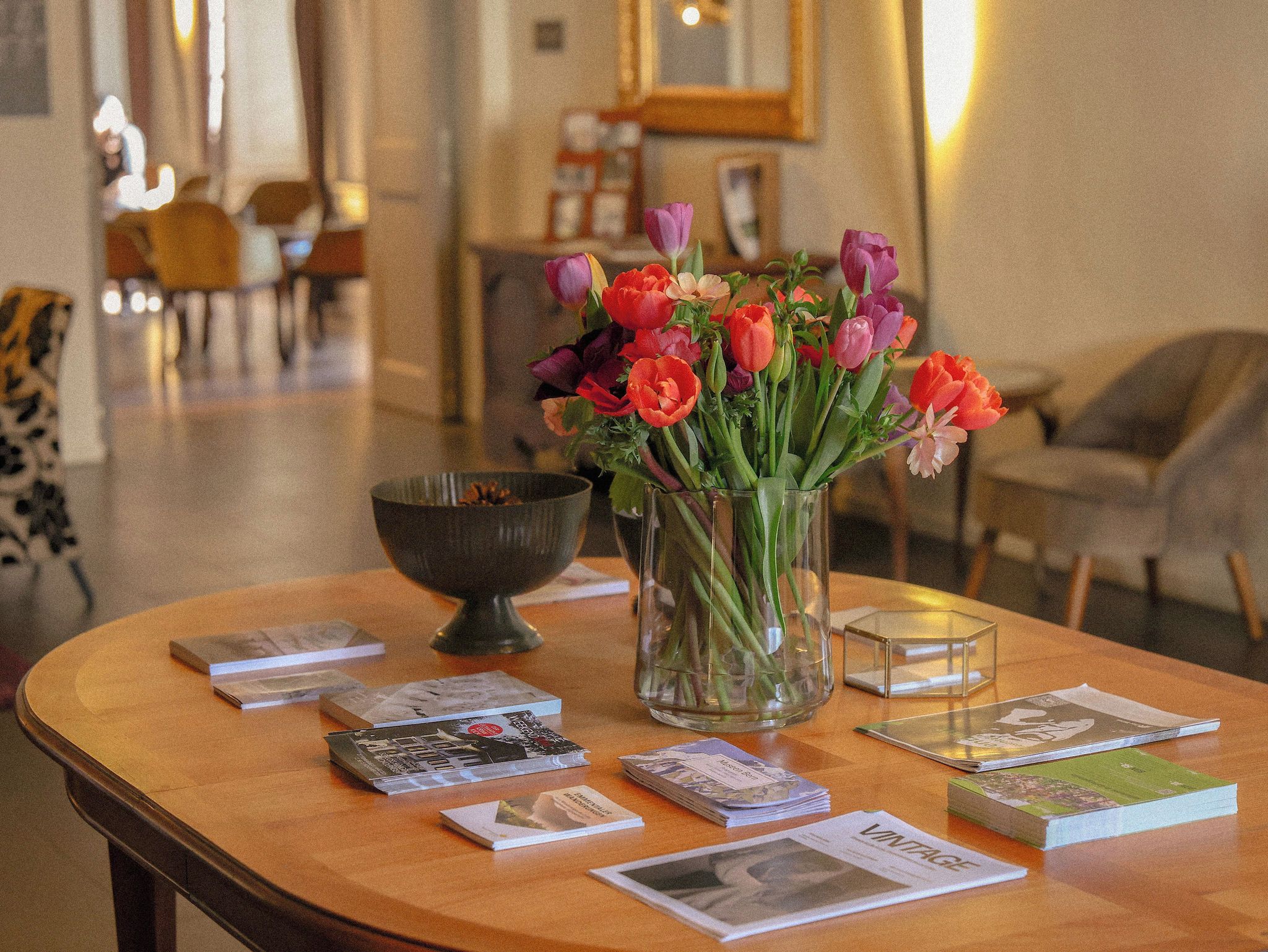Una mesa con un jarrón de tulipanes, un cuenco y algunos libros.