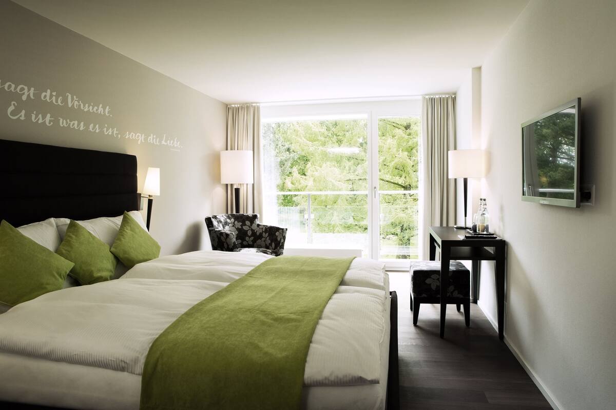 Habitación de hotel con una cama grande, un escritorio, una silla y un televisor.