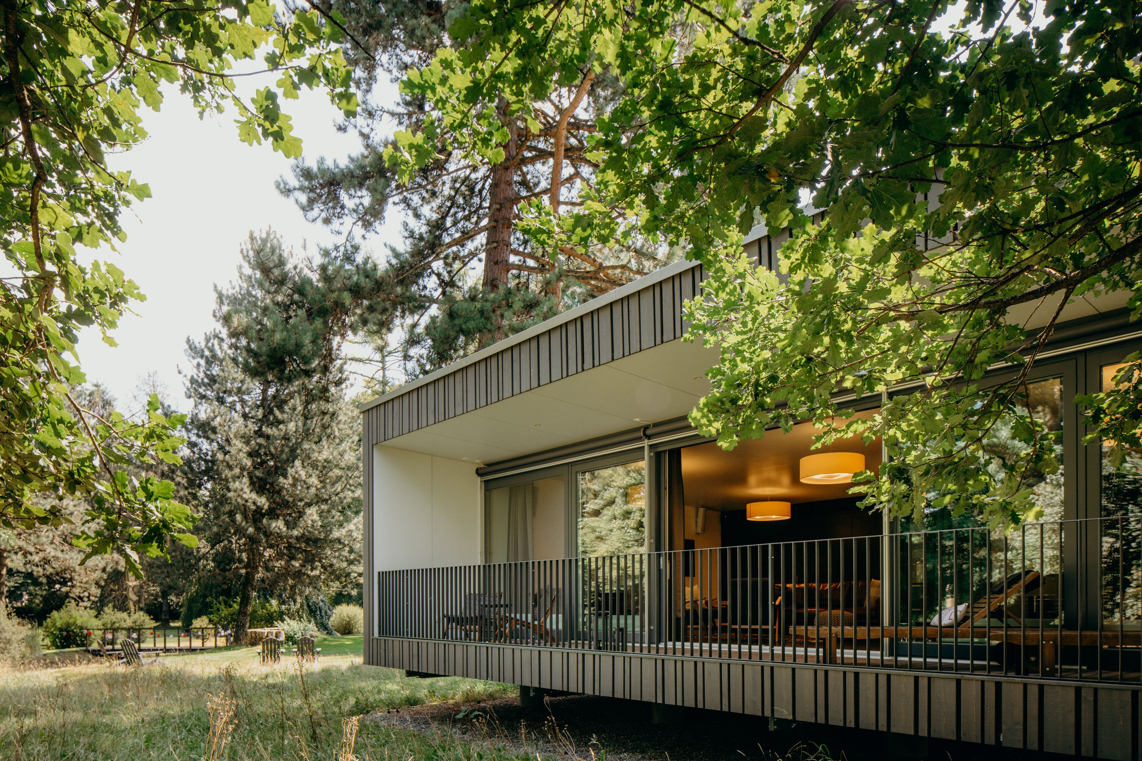 Uma casa moderna com varanda, rodeada por árvores e um jardim bem cuidado.