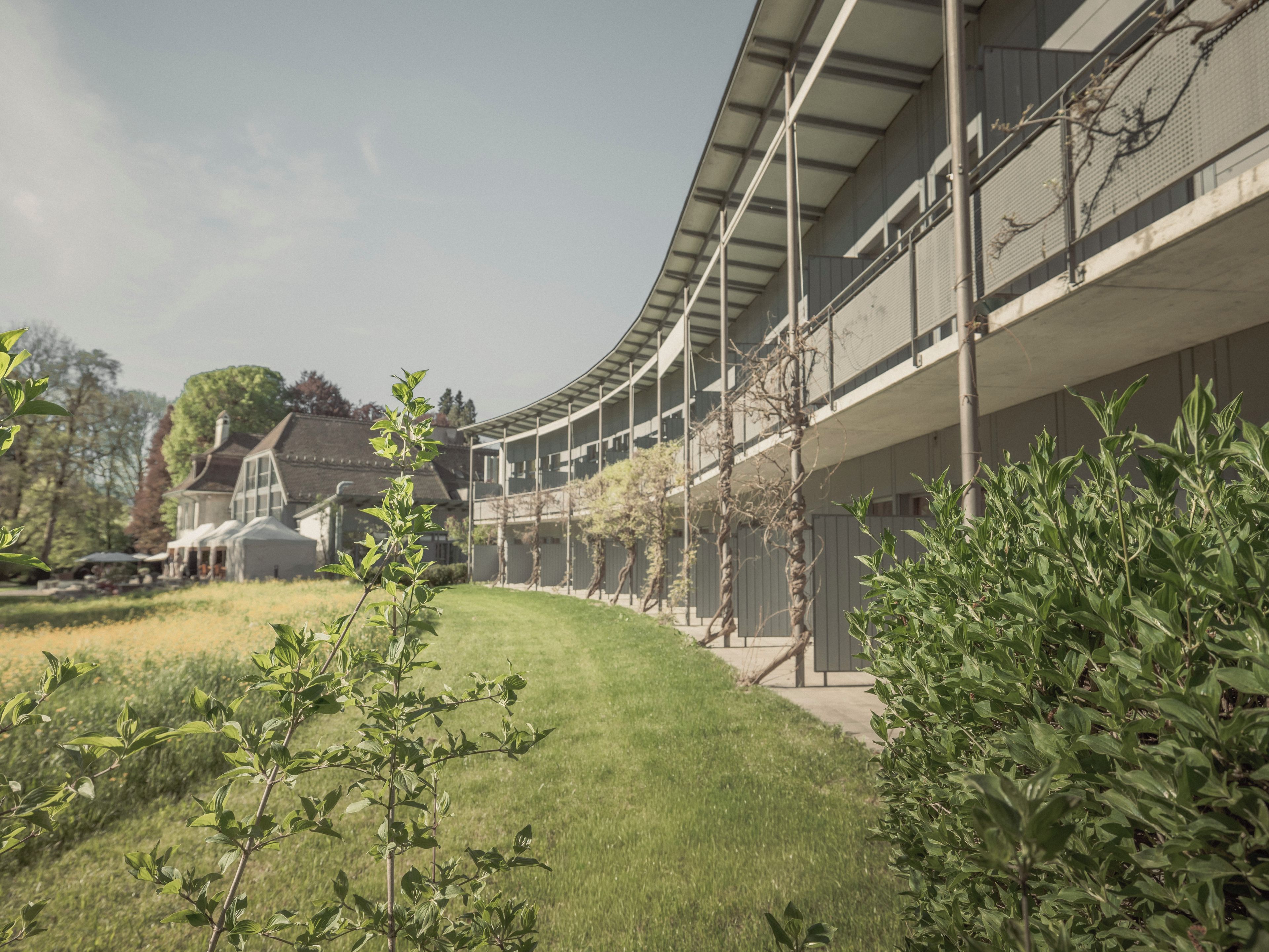 A modern building with a curved roofline, surrounded by well-maintained grass and shrubbery.