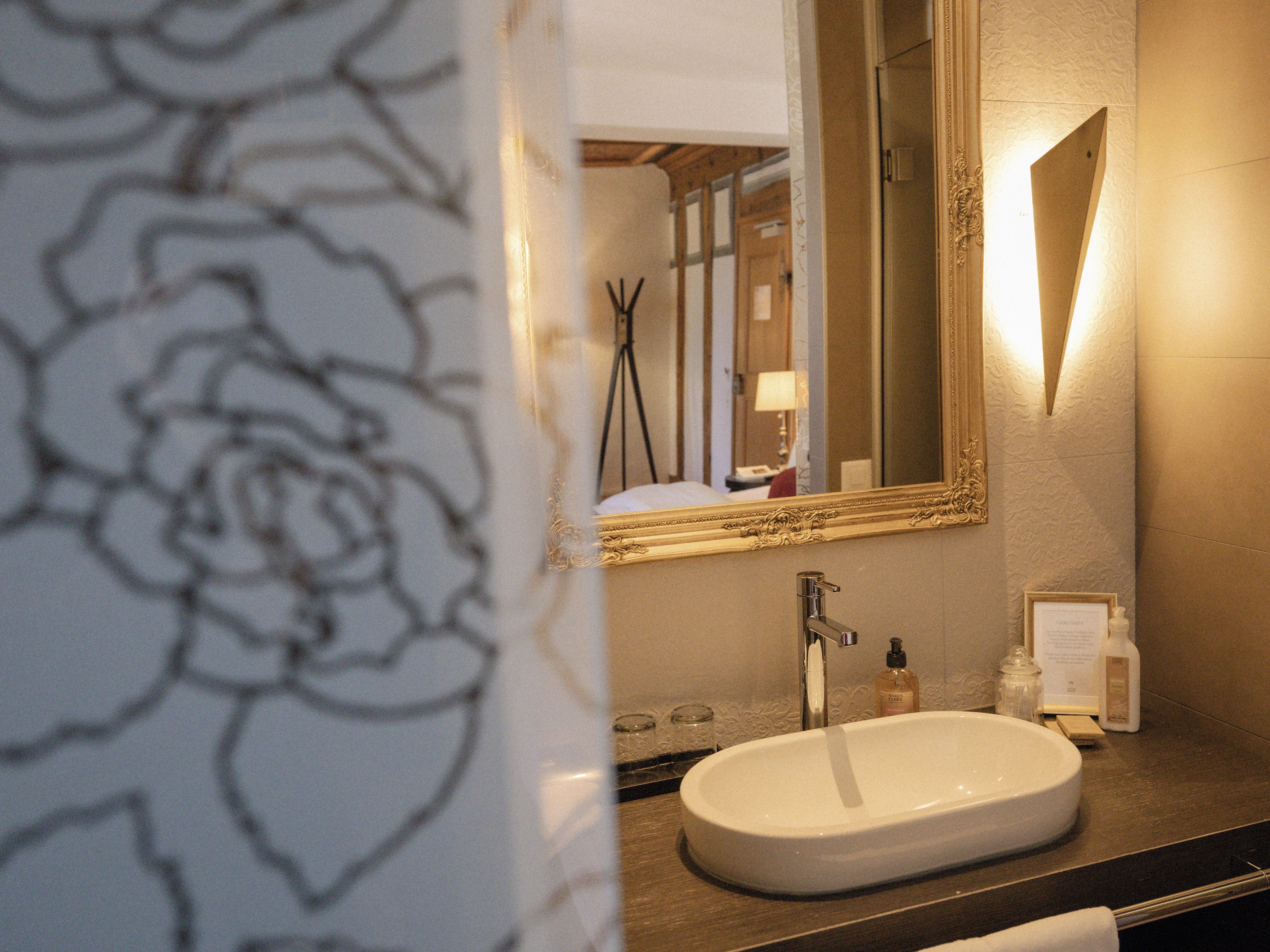 Une salle de bain avec un lavabo blanc, un miroir et un porte-serviettes.