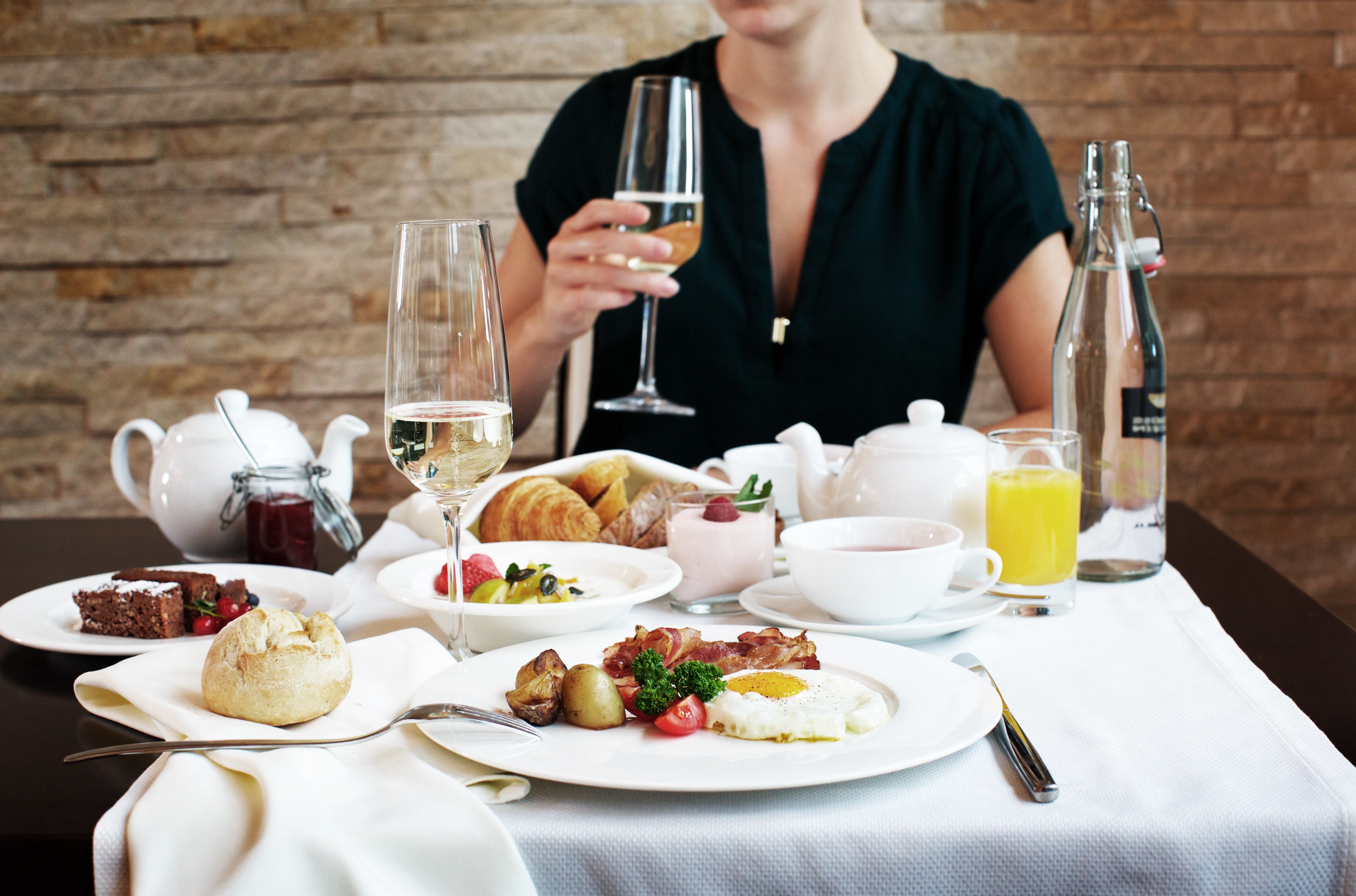 A breakfast setting with a variety of dishes, including eggs, bacon, and pastries, along with beverages and a teapot.
